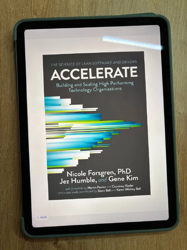 Обложка книги Accelerate Николь Форсгрен, Джеза Хамбла и Джина Кима на экране планшета